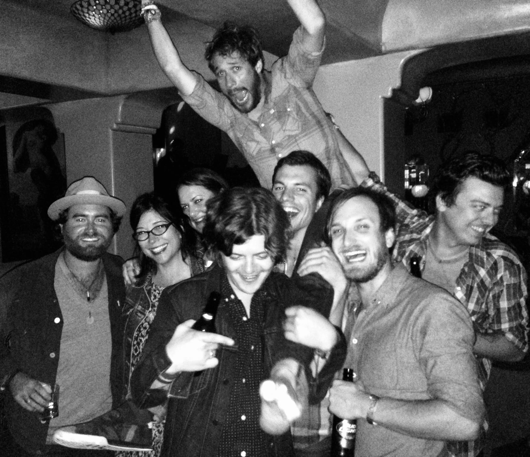 A large group of Wild Feathers members and friends laughing together during an album-release celebration in Los Angeles.