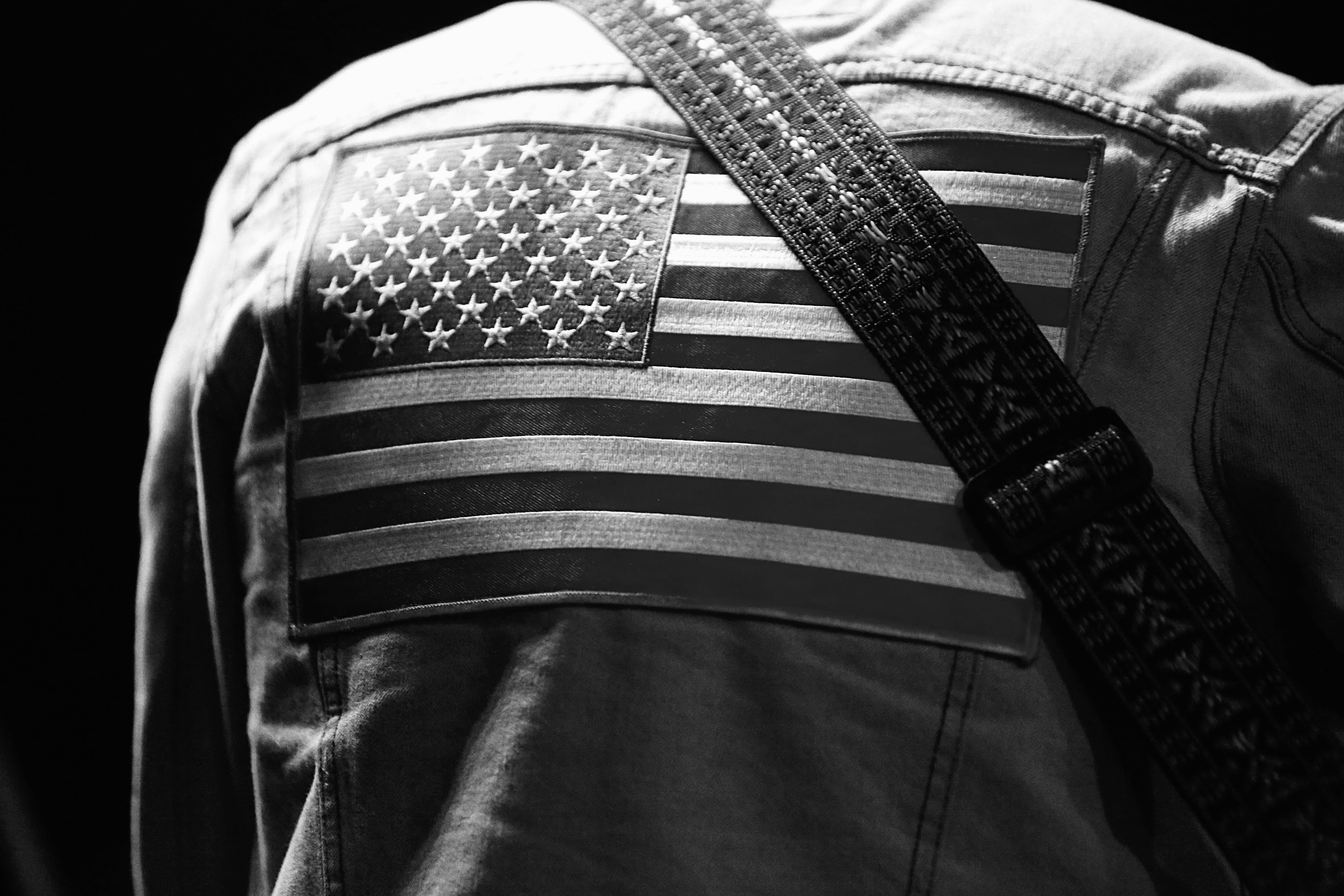 A professional close-up of an American flag patch and guitar strap during a Wild Feathers performance.