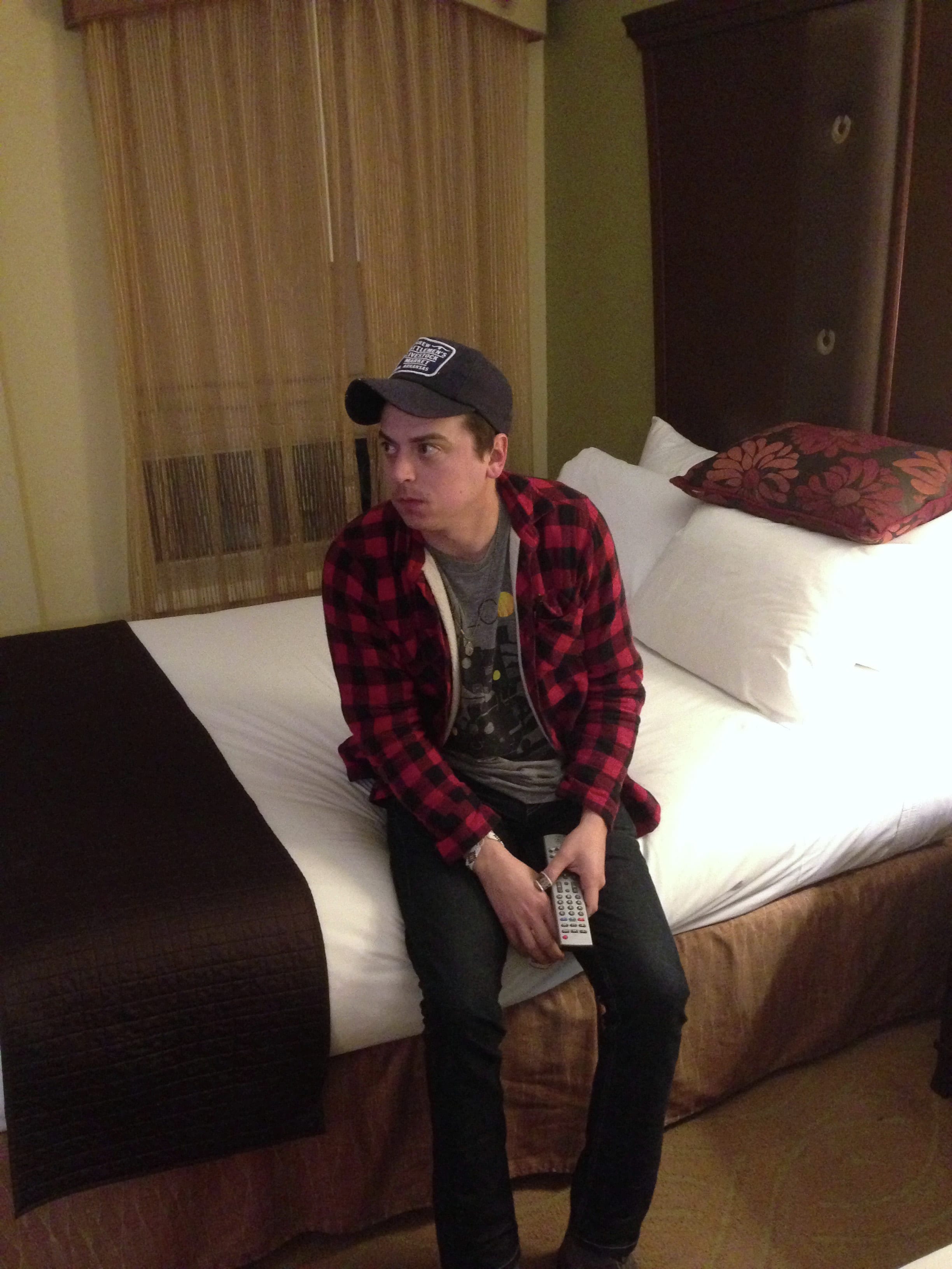 A member of The Wild Feathers sitting on a hotel bed in Birmingham, Alabama.