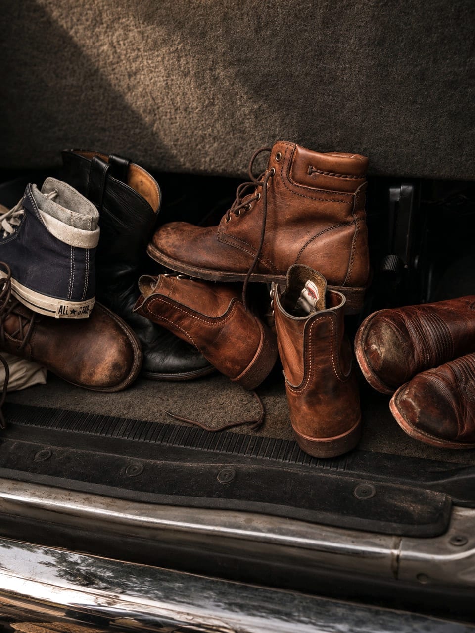 Worn boots and a canvas high-top arranged in the rear of a white van.