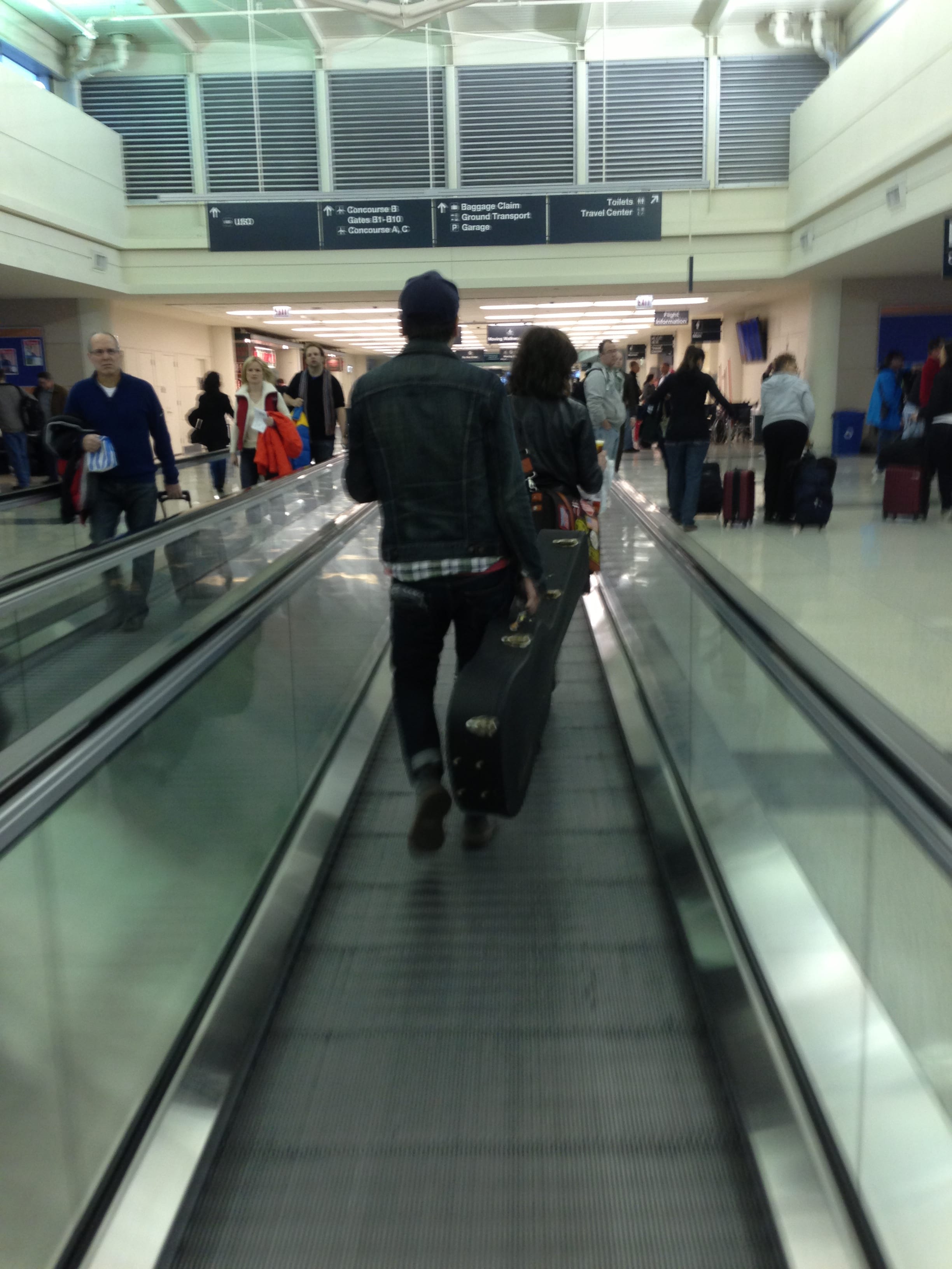 A member of The Wild Feathers on a moving walkway during a connection at Chicago Midway.