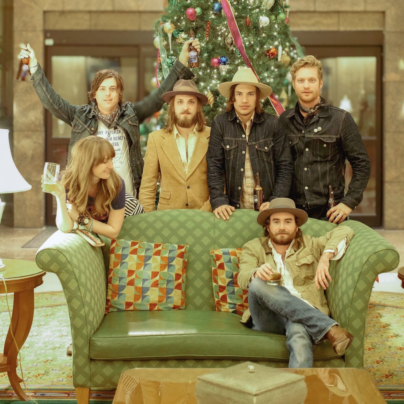 Six people gathered around a green sofa in front of a hotel Christmas tree after the Duluth show.