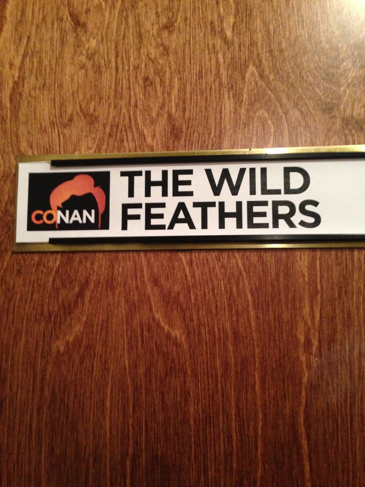 A dressing-room placard bearing the Conan logo and the name The Wild Feathers.