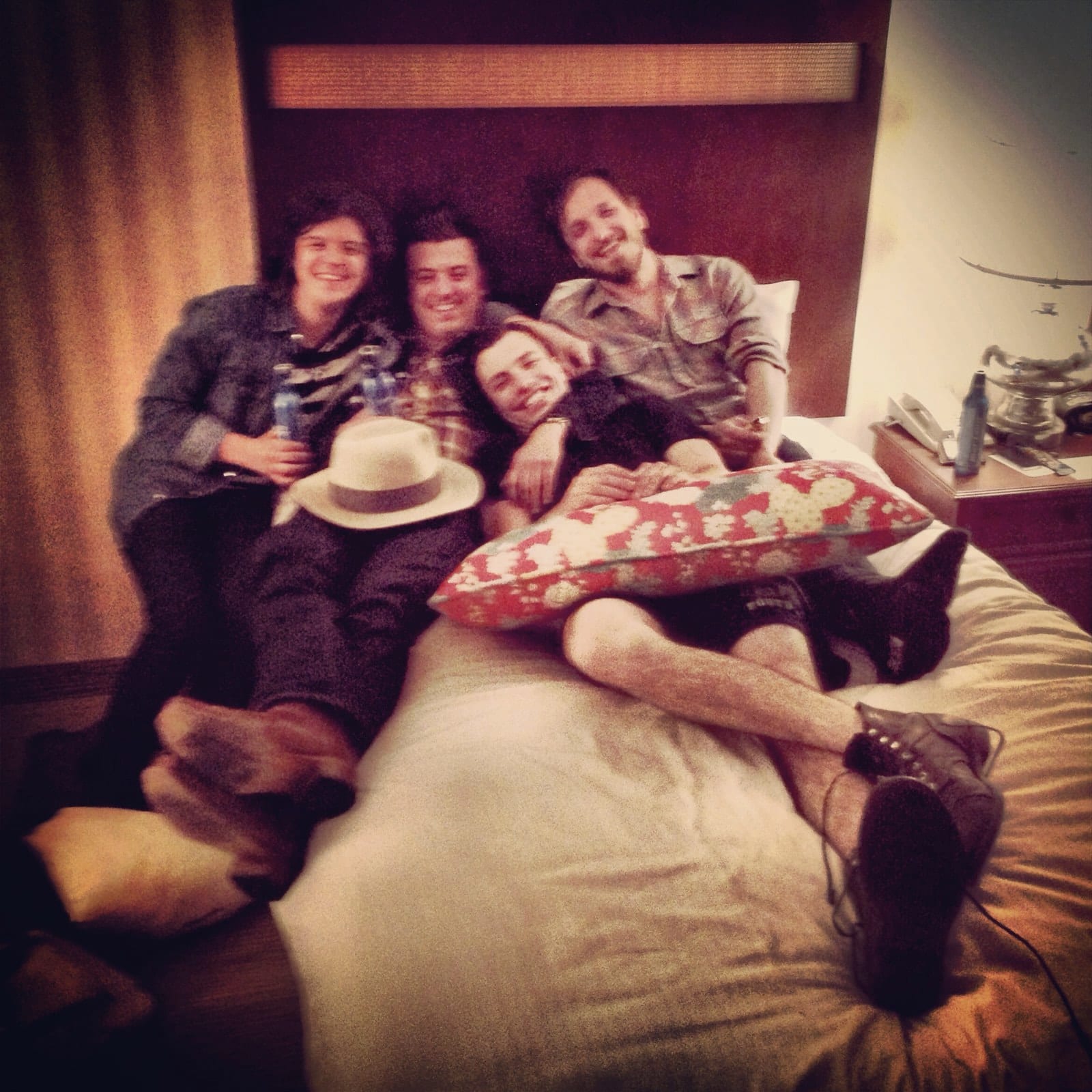 Members of The Wild Feathers and companions relaxing together on a hotel-room bed after the Corpus Christi tour stop.
