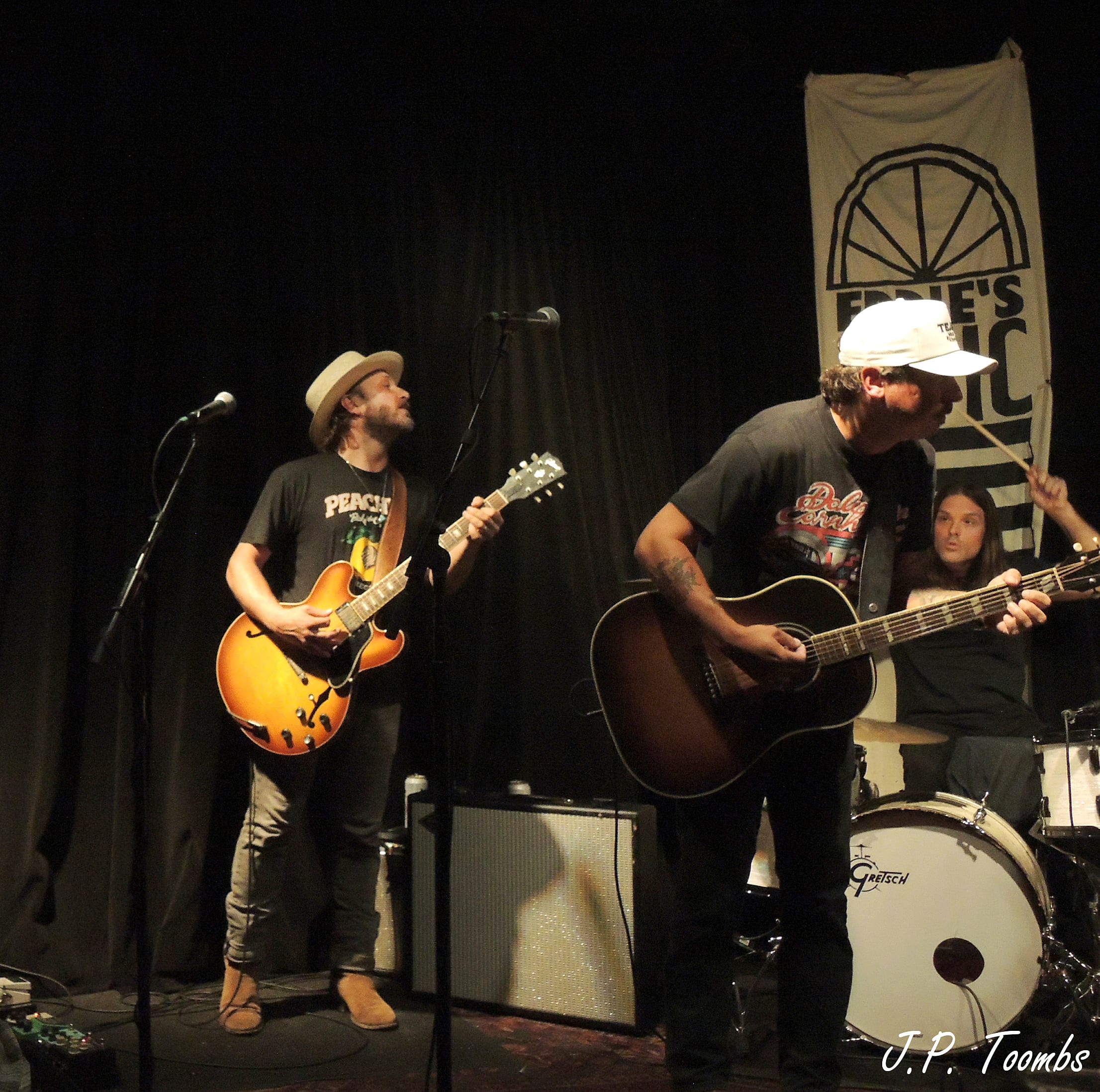 Two Wild Feathers guitarists play close together on the small Eddie's Attic stage while Nigel Dupree sits at the drum kit.