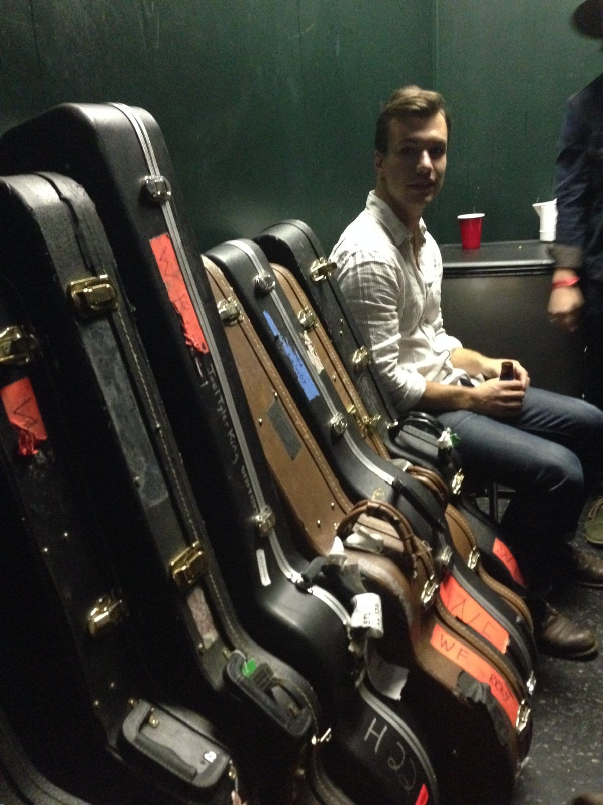 A member of The Wild Feathers sitting among guitar and equipment cases at the St. Louis stop.