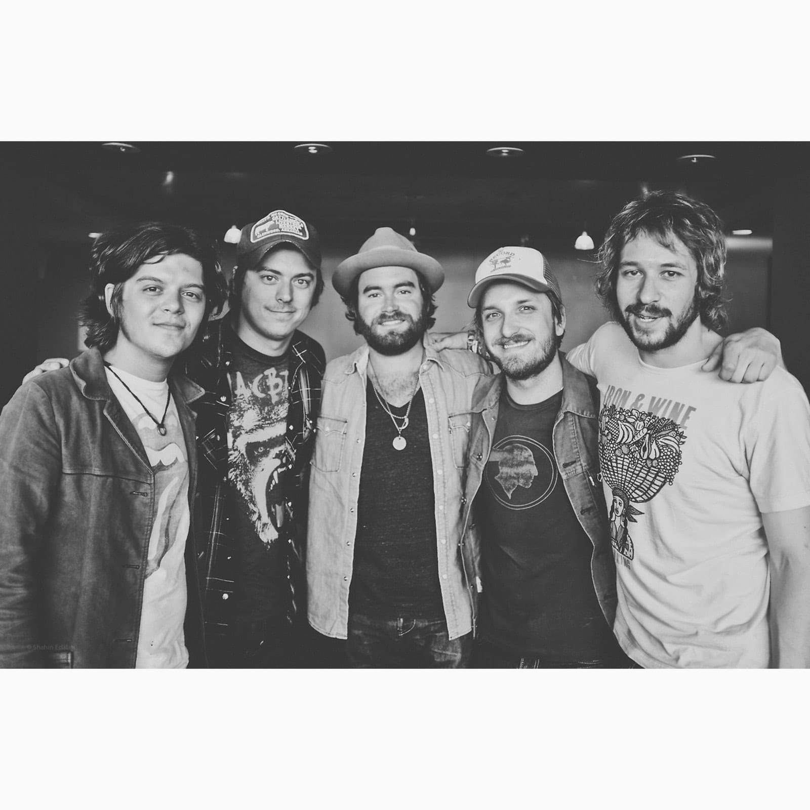 A black-and-white portrait shows the five touring members of The Wild Feathers standing shoulder to shoulder.