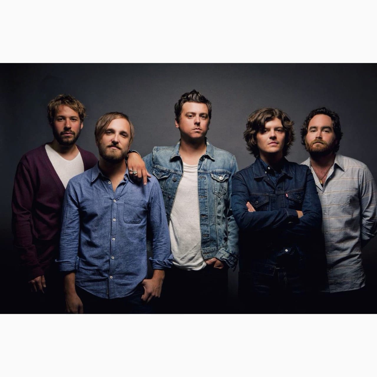 Formal color portrait of five unidentified Wild Feathers members standing against a dark studio backdrop.