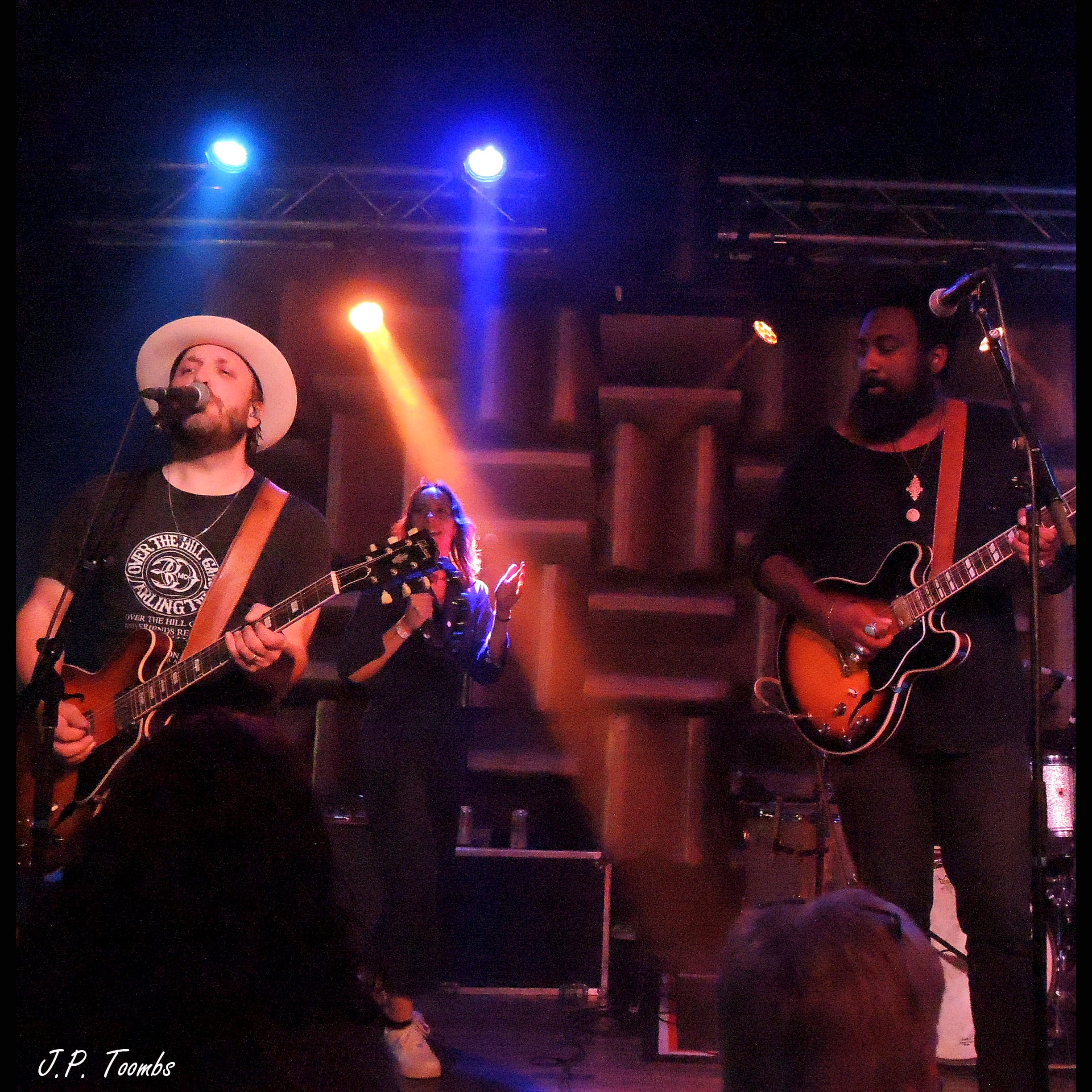 Guest guitarist Nathan Graham plays beside two members of The Wild Feathers under blue and amber stage lights at HI-FI Indy.