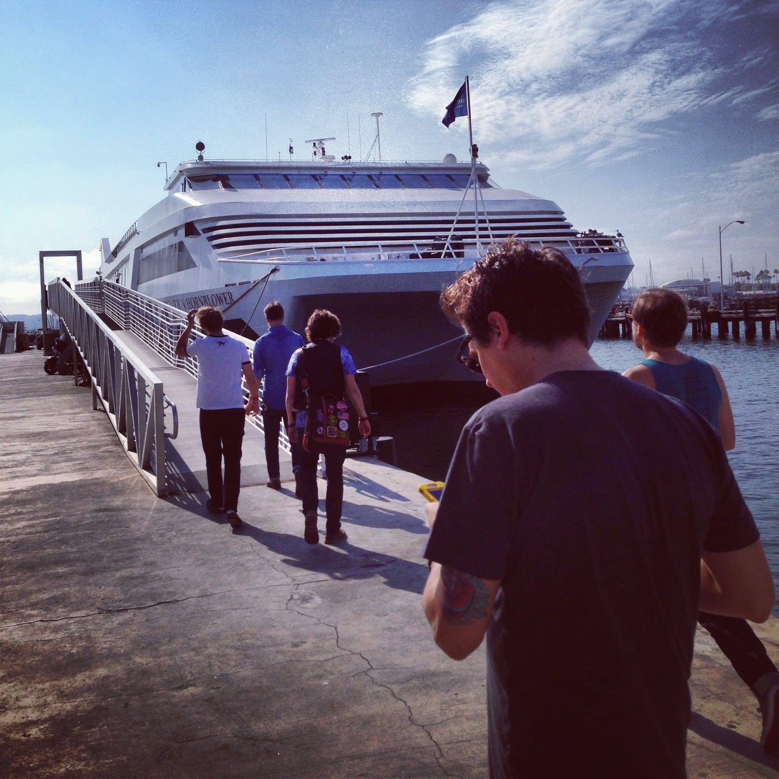 Members of the touring party walking toward a docked Hornblower cruise ship in San Diego.