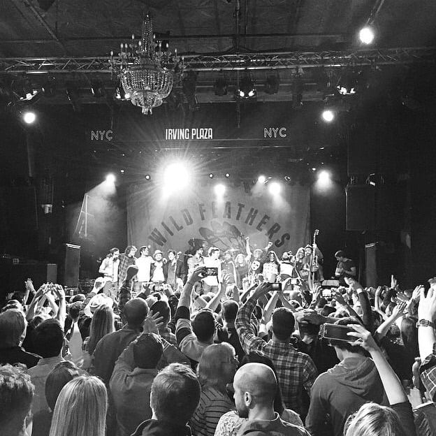 Black-and-white view from the Irving Plaza audience of a crowded Wild Feathers stage beneath the venue's NYC signage.