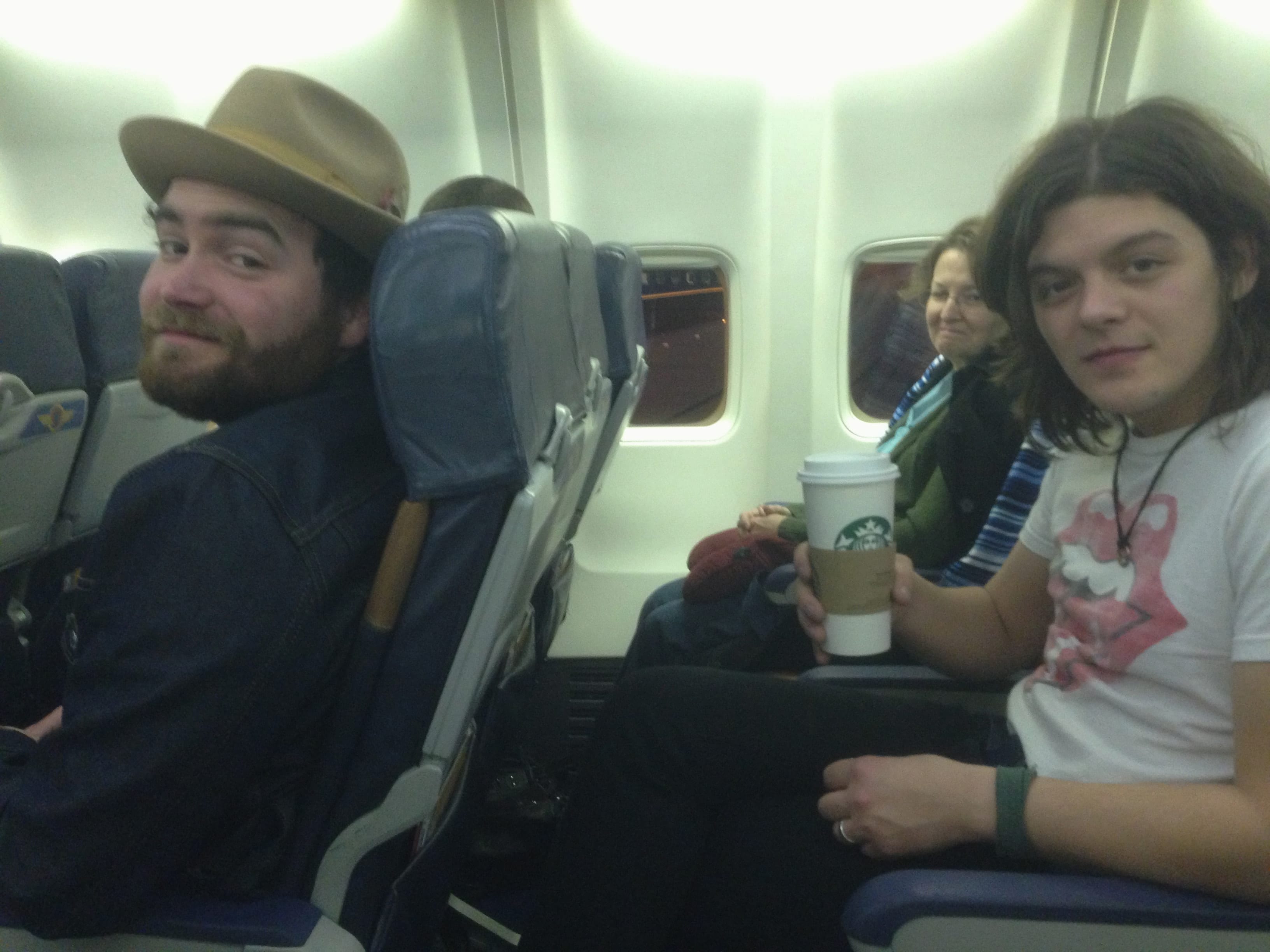Two members of The Wild Feathers seated aboard an airplane at the start of the Sunset Sessions trip.