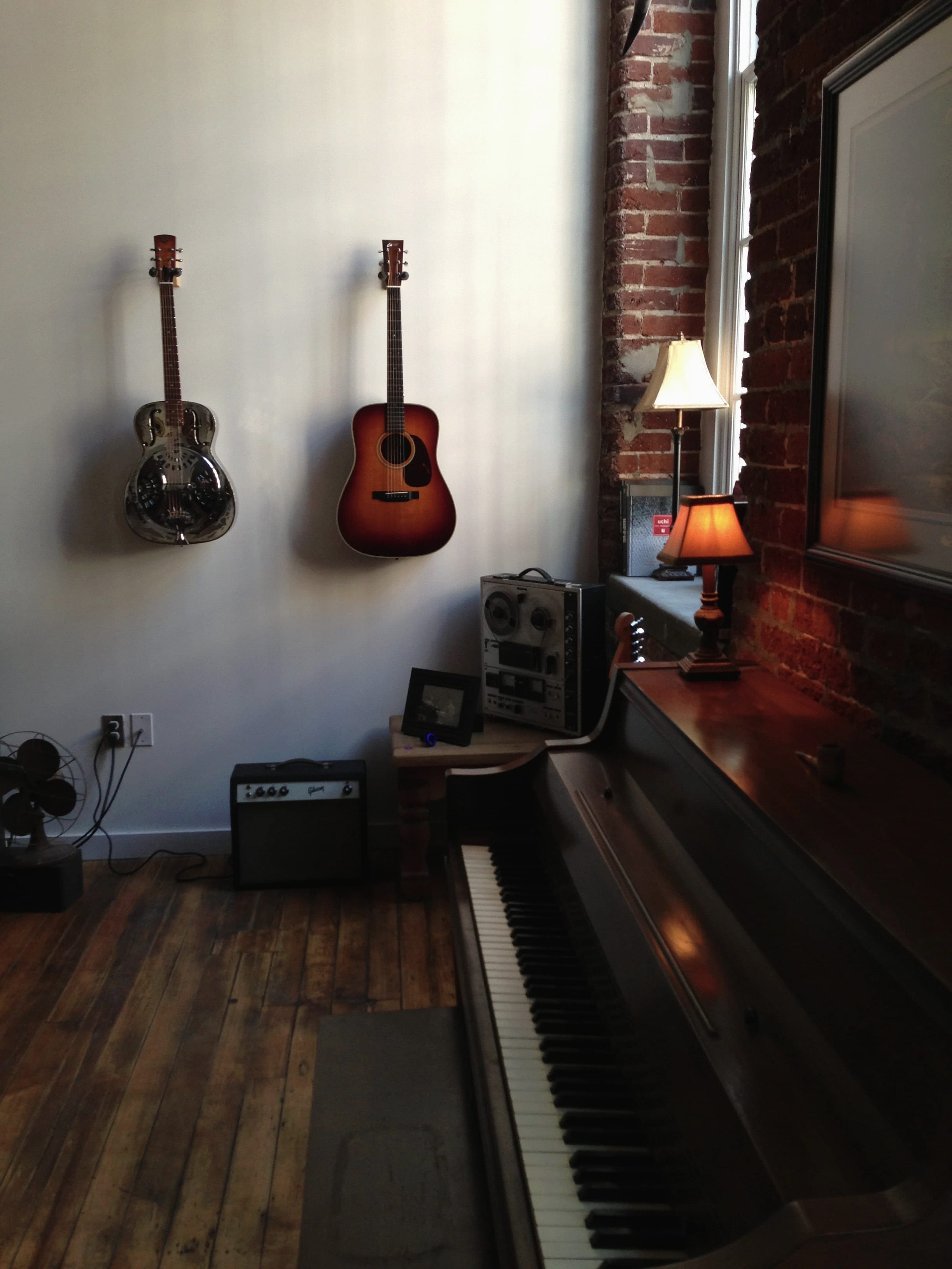 A quiet brick-walled Nashville room with guitars, records, amplifiers, piano, and reel-to-reel recorder.