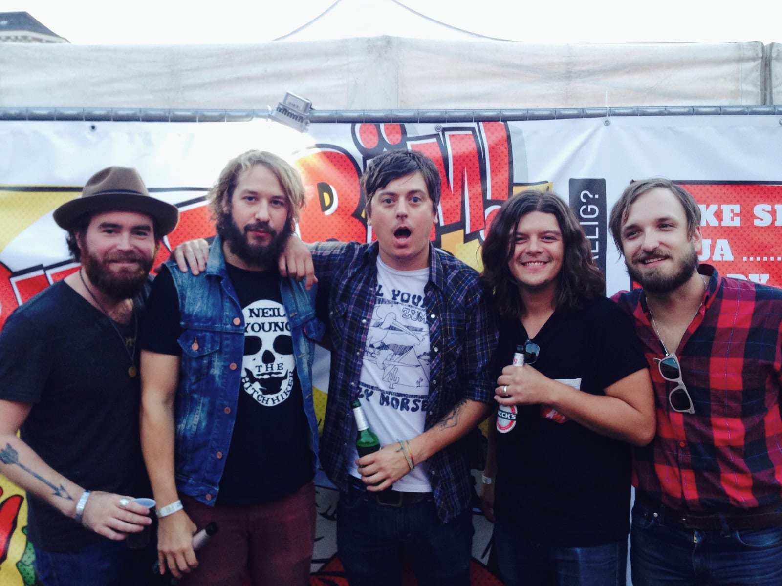 The five touring members of The Wild Feathers pose together in front of colorful Reeperbahn Festival signage.