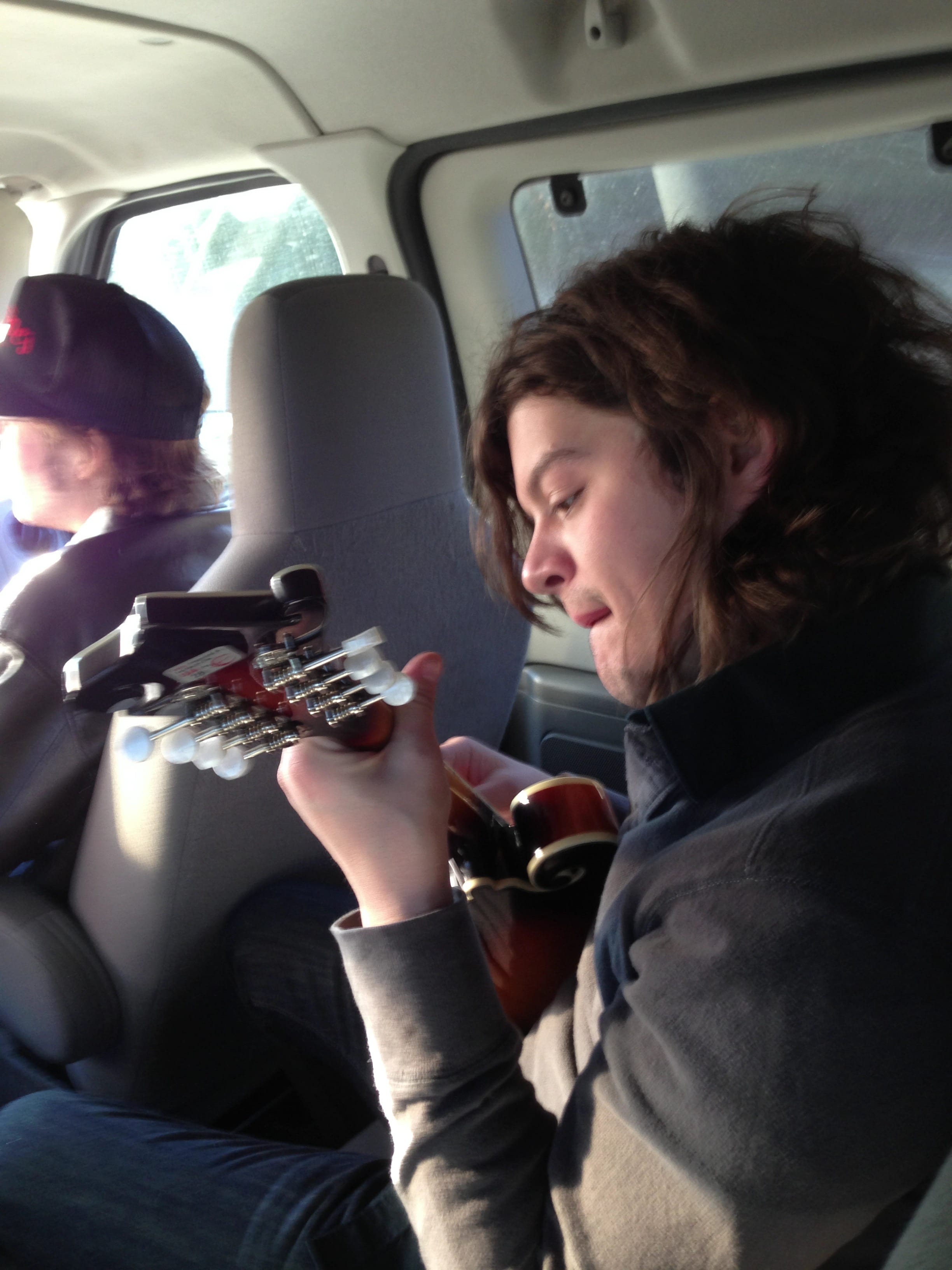 A member of The Wild Feathers playing guitar inside the van near Livingston, Alabama.