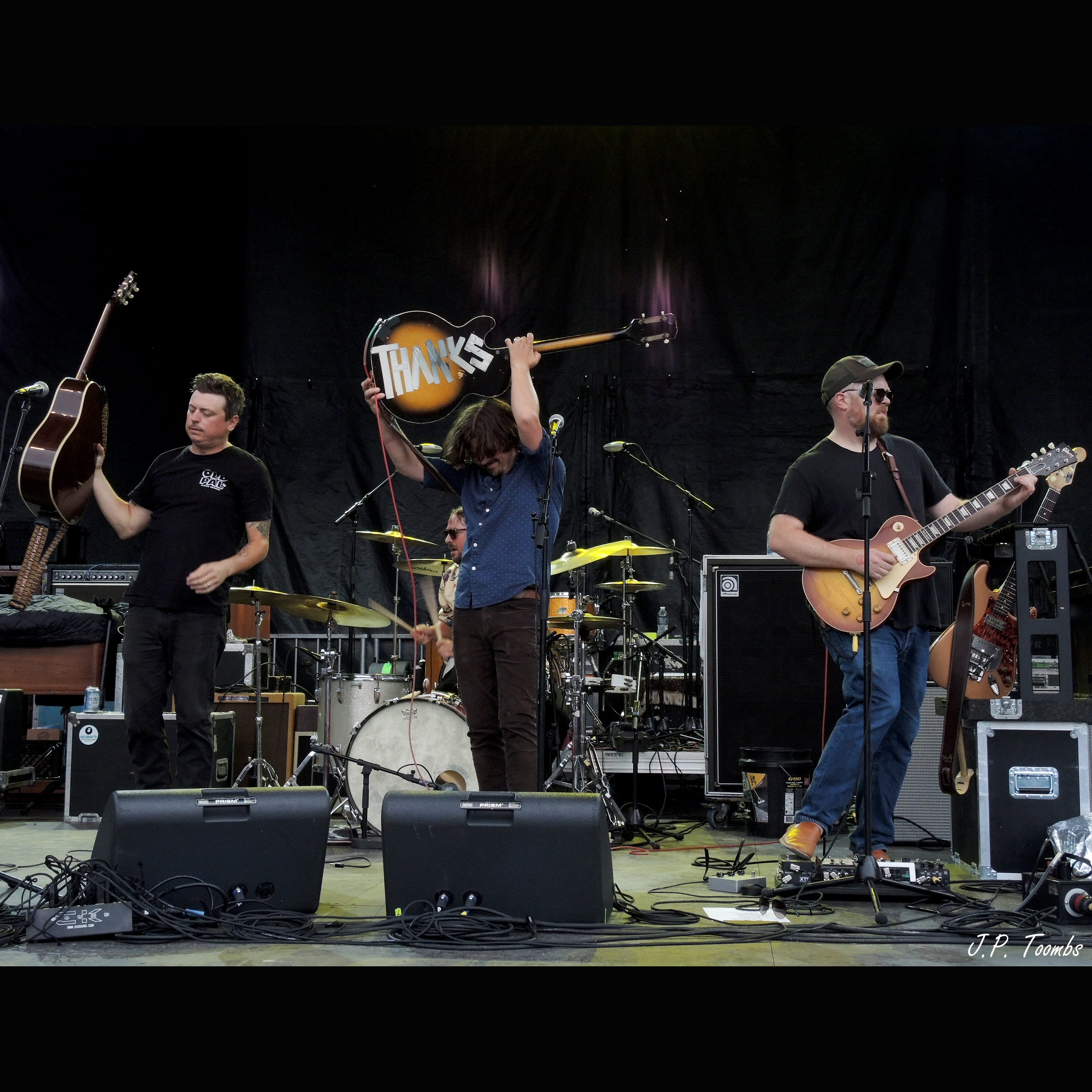 A Wild Feathers member holds a handmade THANKS sign overhead while the band remains onstage at Rock the Ruins.