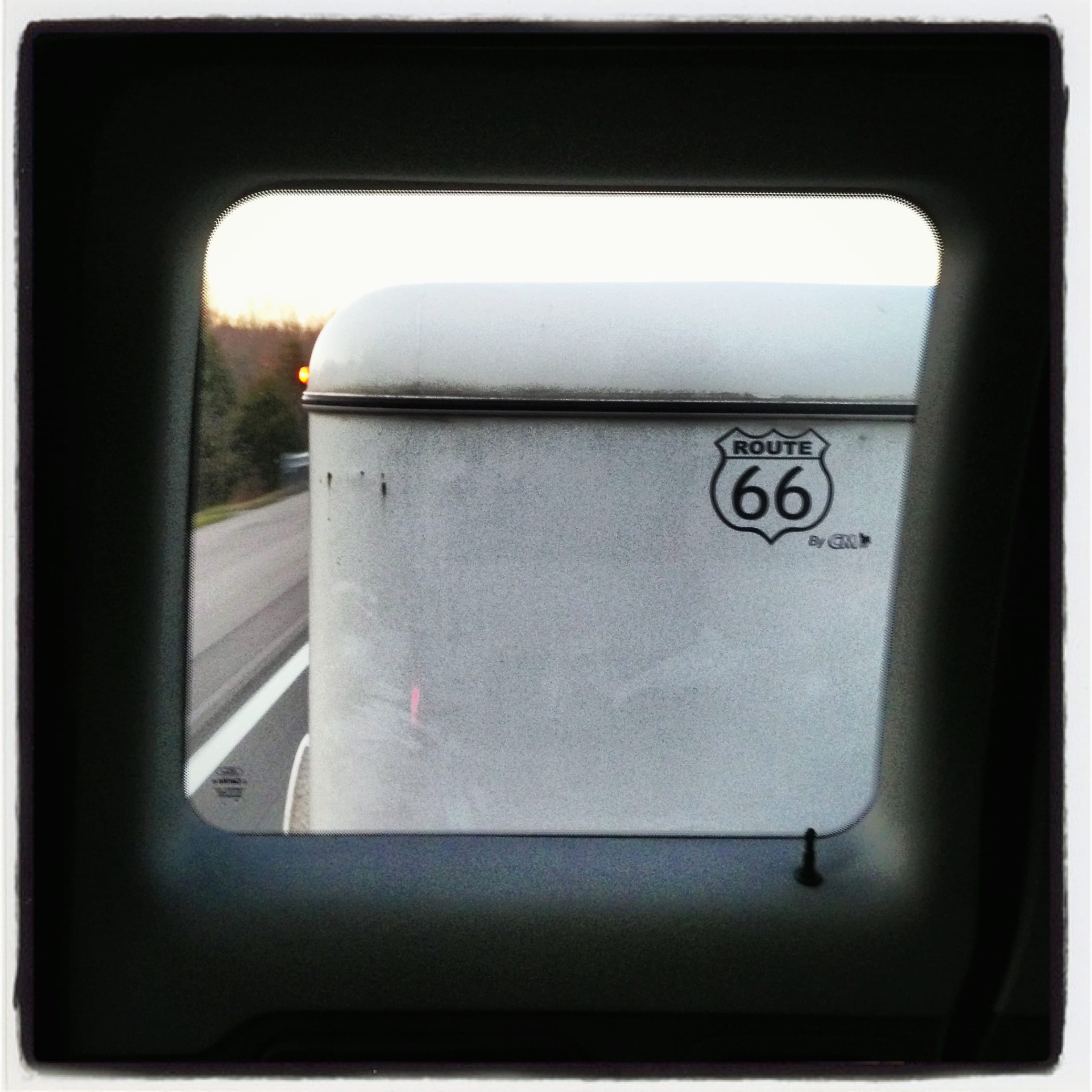 A roadside Route 66 shield photographed through a vehicle window.