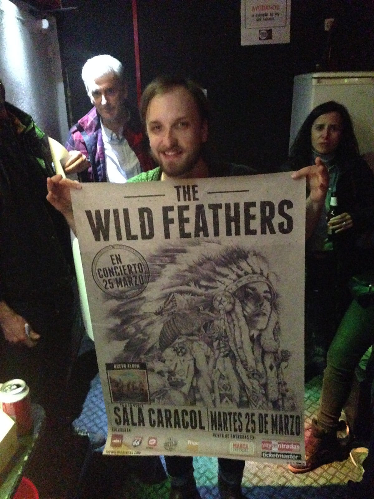 A person holding a Wild Feathers Sala Caracol concert poster inside the Madrid venue.