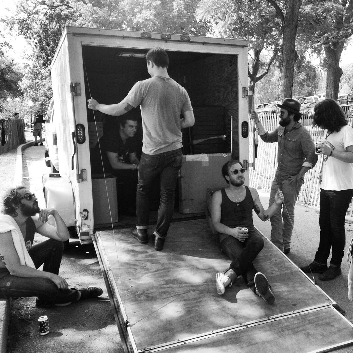 Black-and-white photograph of band and crew gathered around an open equipment trailer in Sioux City.