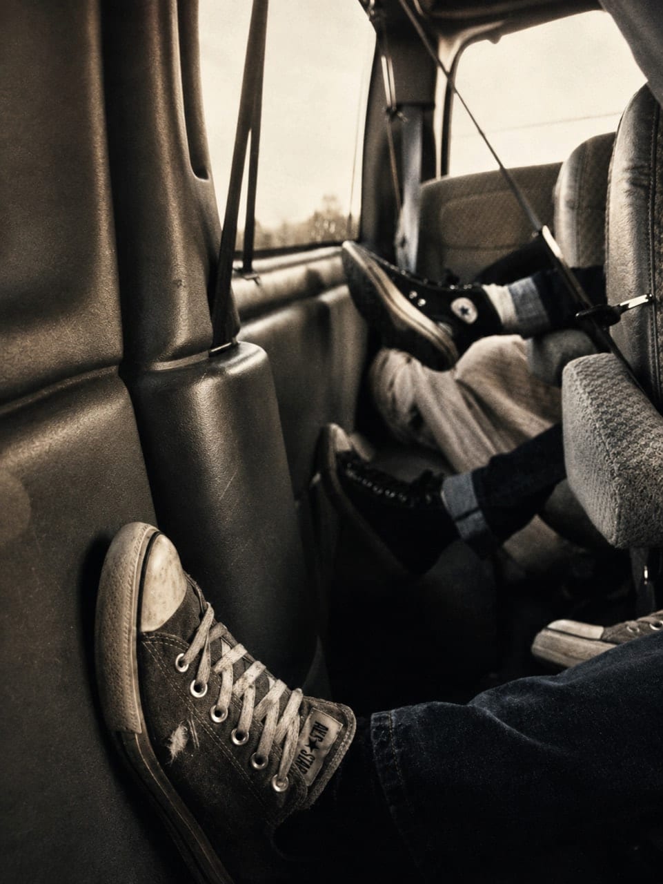 Several band members' legs and shoes tangled together while sleeping inside the van.