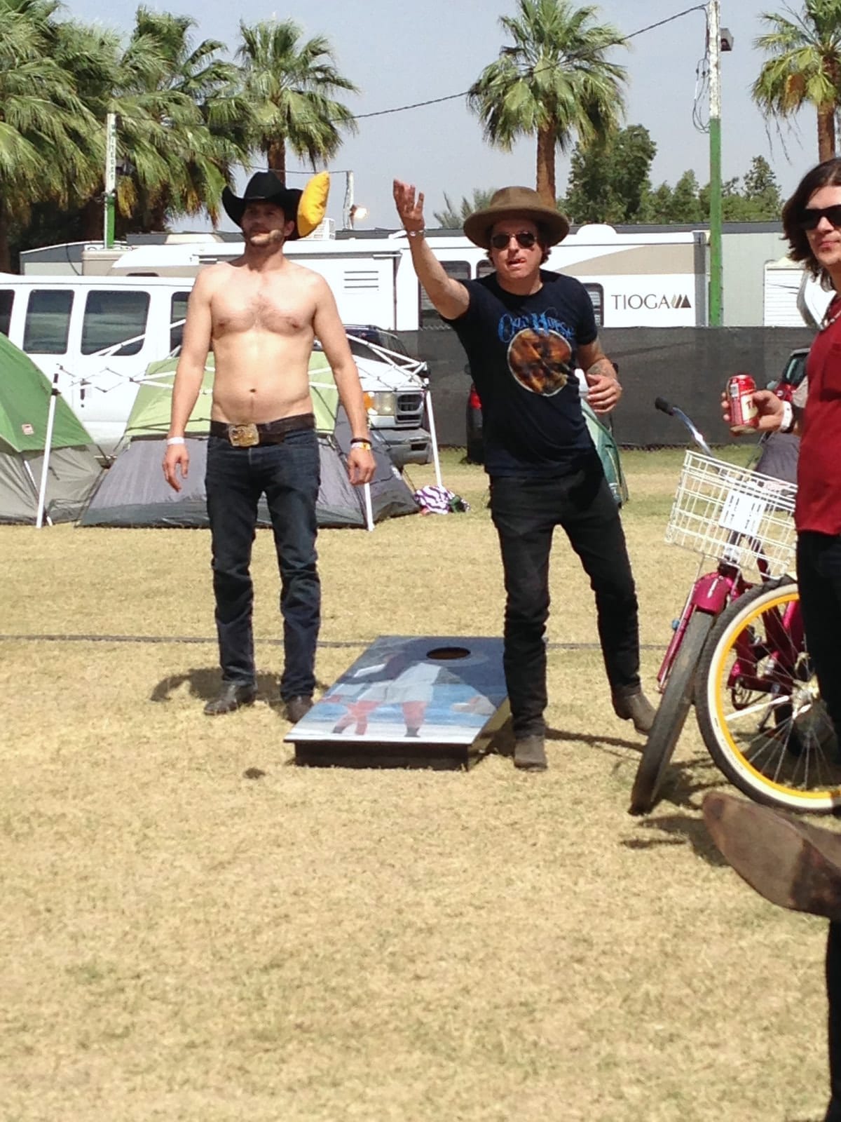 Two members of The Wild Feathers standing near a lawn game in the Stagecoach festival grounds.