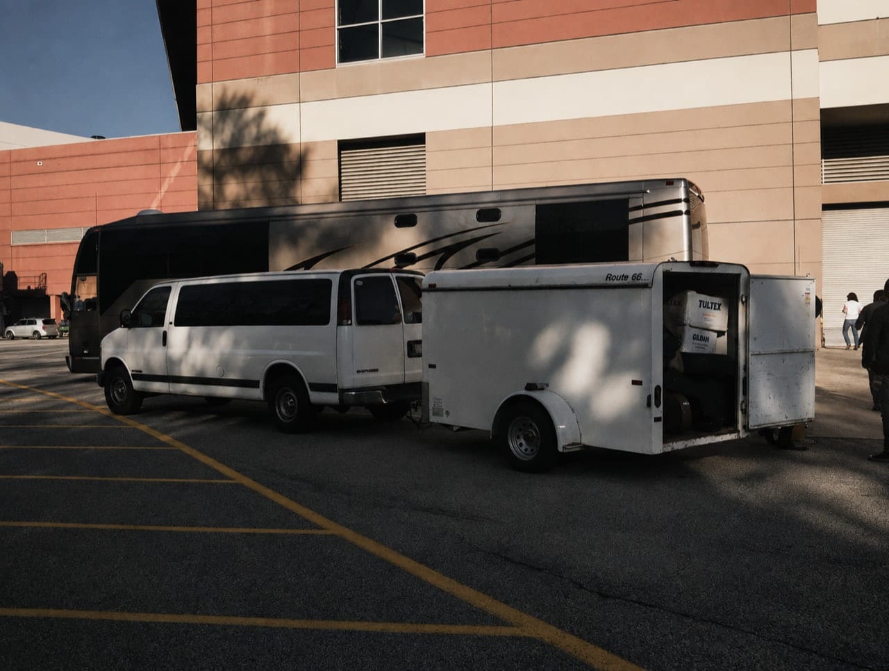 The Wild Feathers' white Ford van and Route 66 trailer parked beside a large tour bus in Duluth, Georgia.
