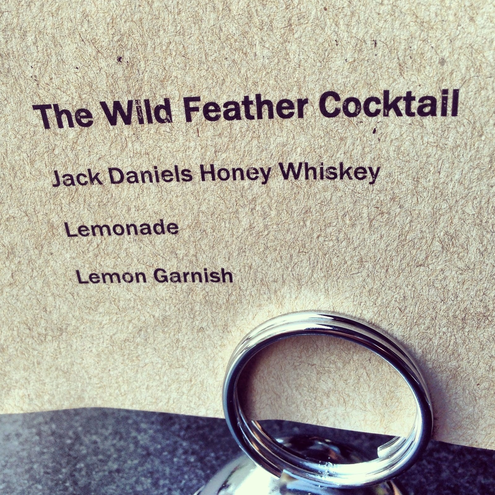 A printed Wild Feather cocktail recipe beside a drink at the New York stop.