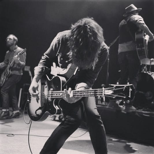 A square black-and-white derivative of Brandon Wu's photograph of The Wild Feathers performing at the 9:30 Club.