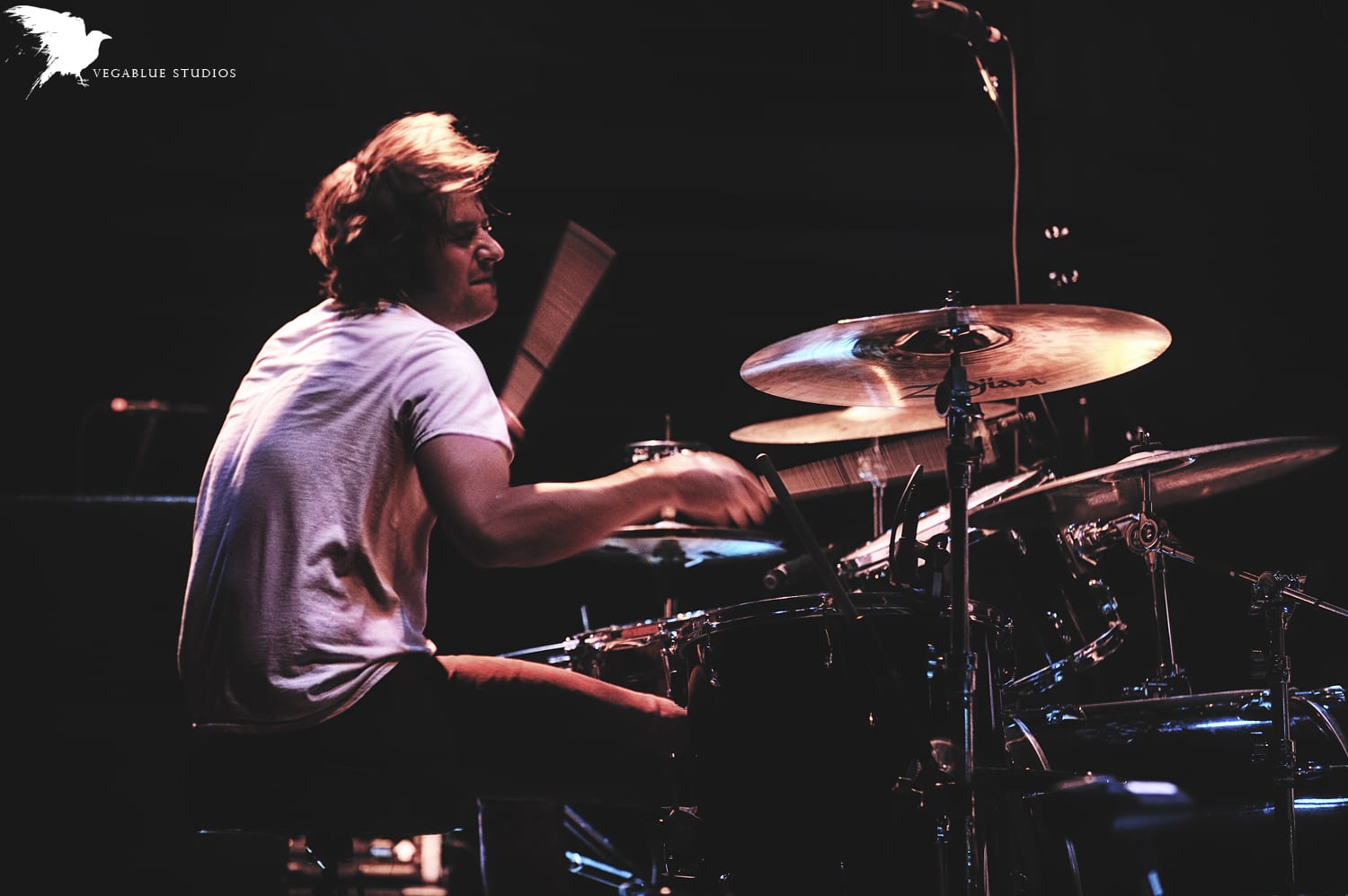 A professional live photograph of The Wild Feathers drummer, carrying a visible Vegablue Studios watermark.